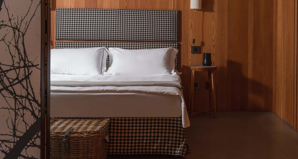 Camera da letto con testiera a quadri, pareti in legno e arredo minimalista.