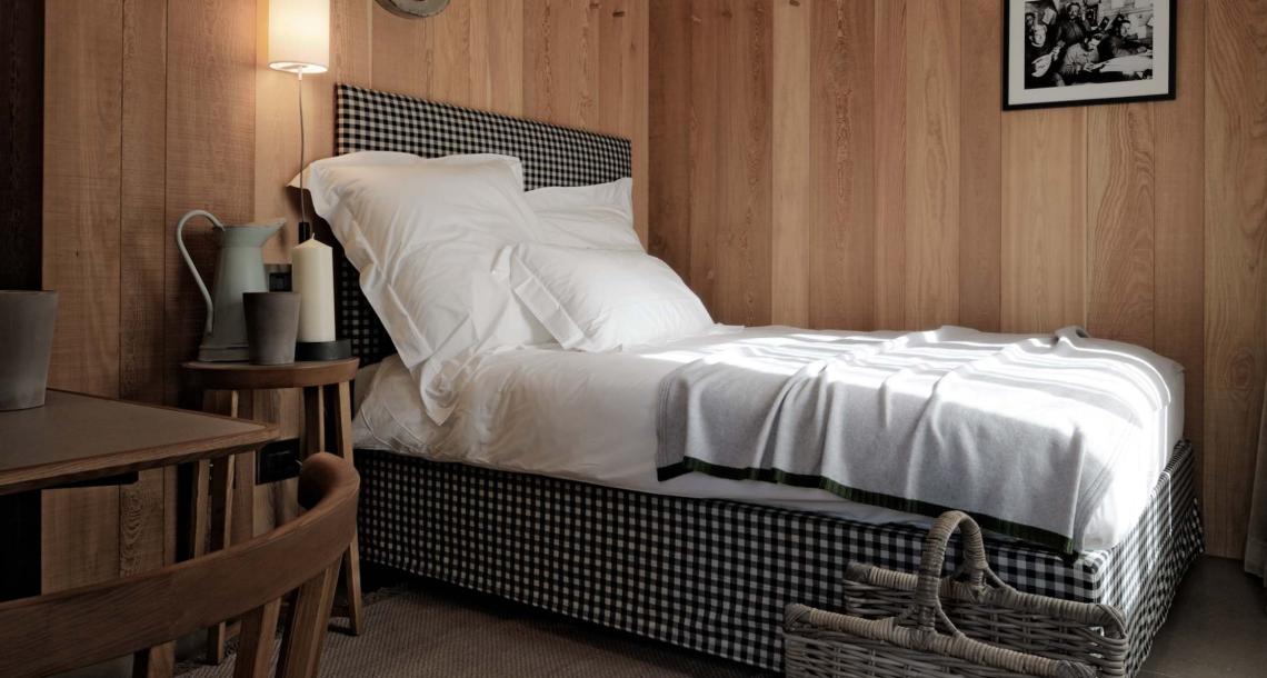 Camera accogliente con letto a quadri e pareti in legno, decorazione minimalista.