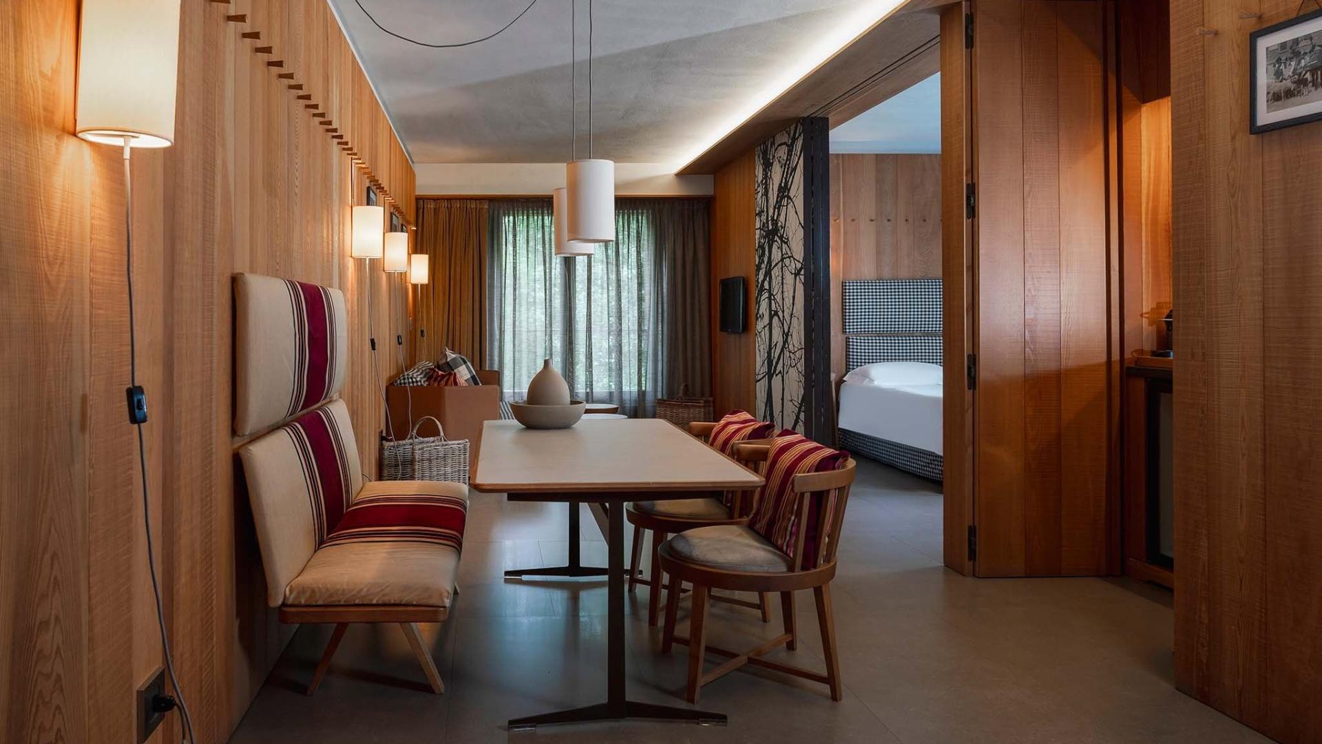Interno moderno con legno, tavolo, sedie e camera da letto in vista.
