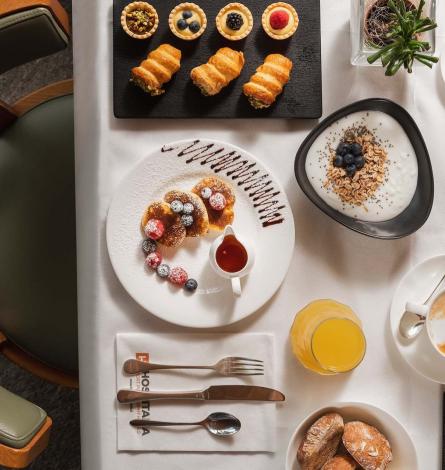 Colazione elegante con dolci, yogurt, frutta, succo d'arancia e bevanda calda.