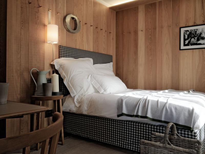Camera accogliente con letto a quadri, pareti in legno e decorazioni semplici.