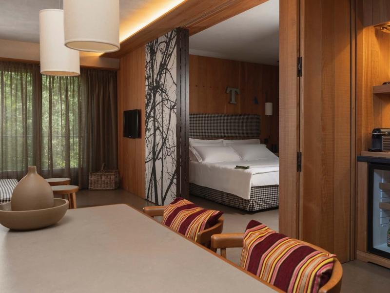 Camera moderna con minibar, letto matrimoniale e decorazioni in legno.