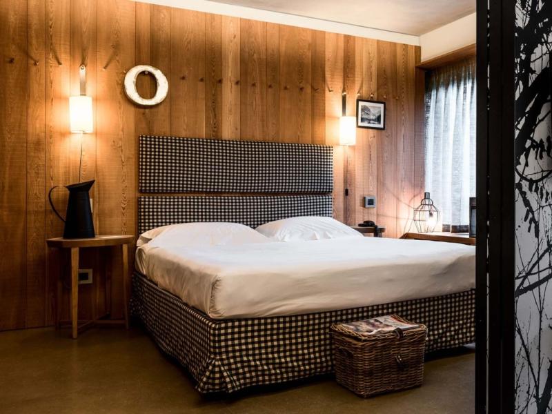 Camera accogliente con letto matrimoniale, pareti in legno e decorazioni moderne.