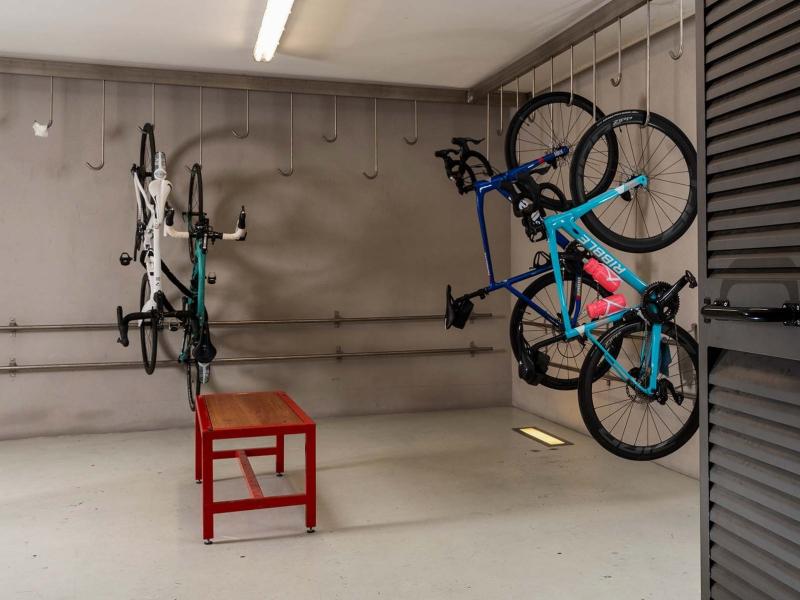 Stanza per biciclette con ganci a parete e una panca rossa.